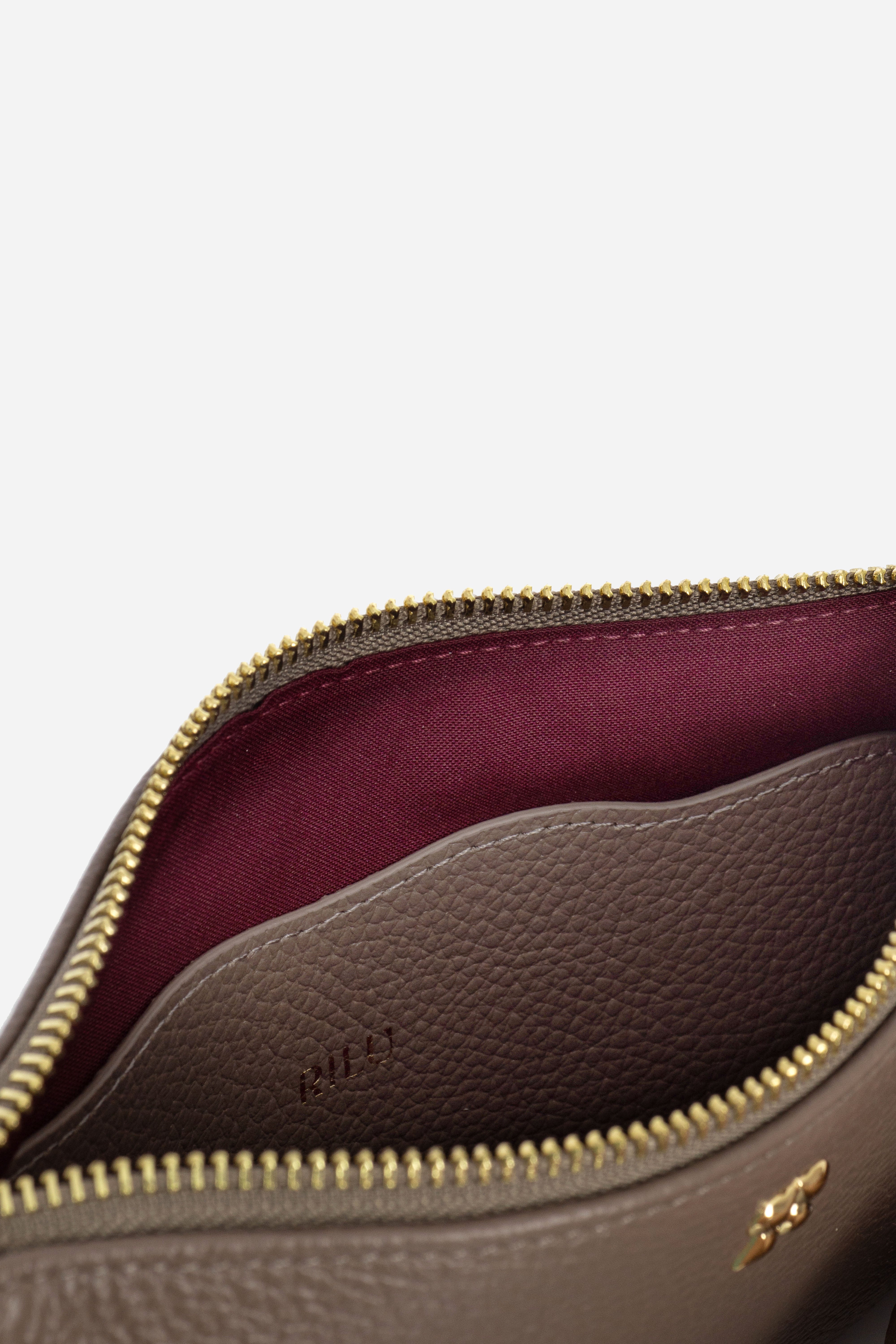 Rilu Kaia taupe clutch close-up of Rilu charm and chain detail