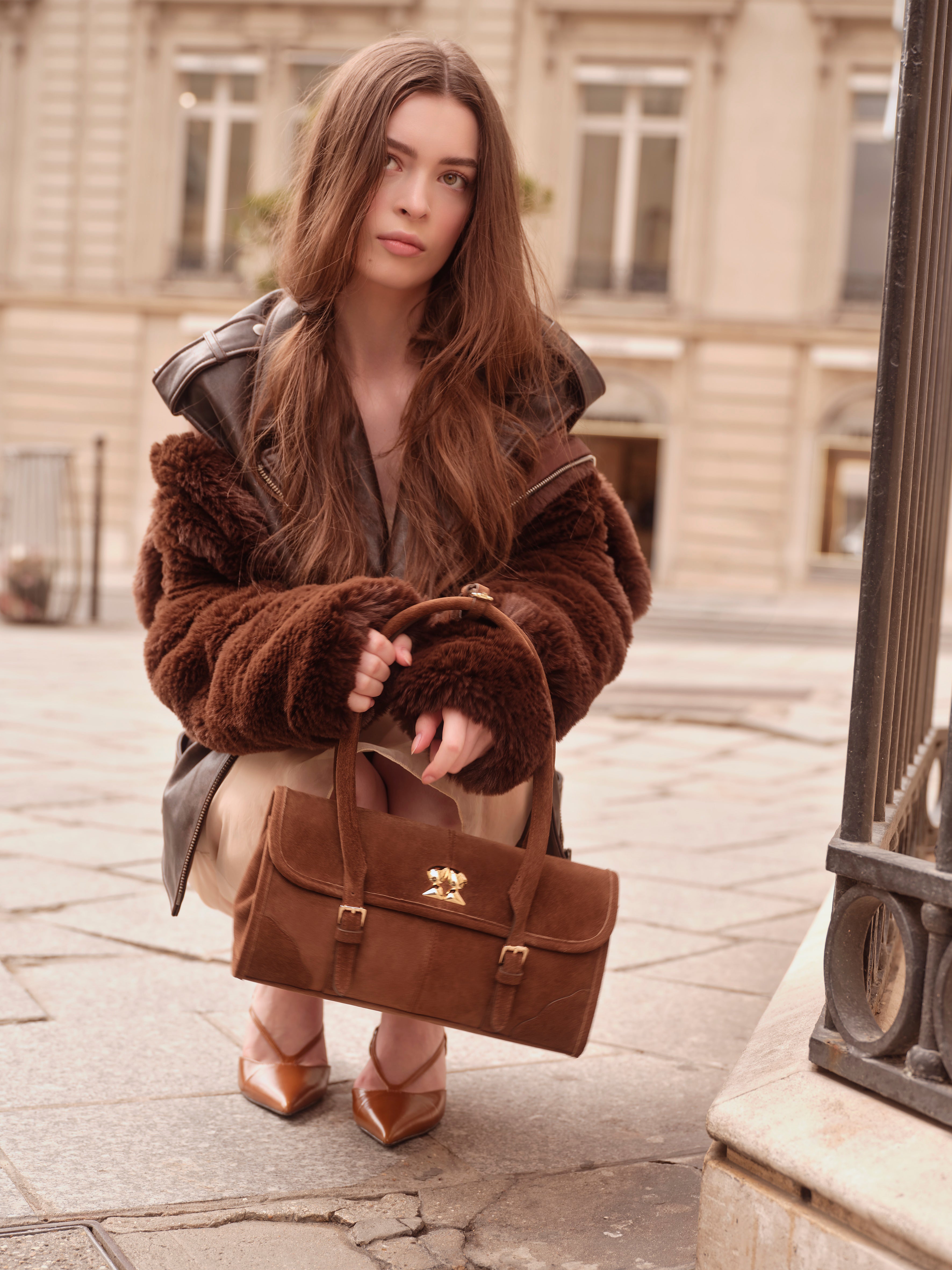 Model holding a Rilu brown suede handbag in street style setting
